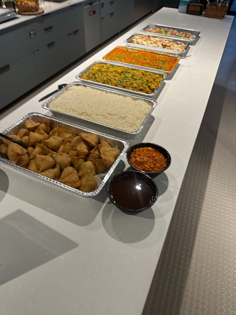 A buffet line of Indian food, including samosas, rice, curries, and naan bread.
