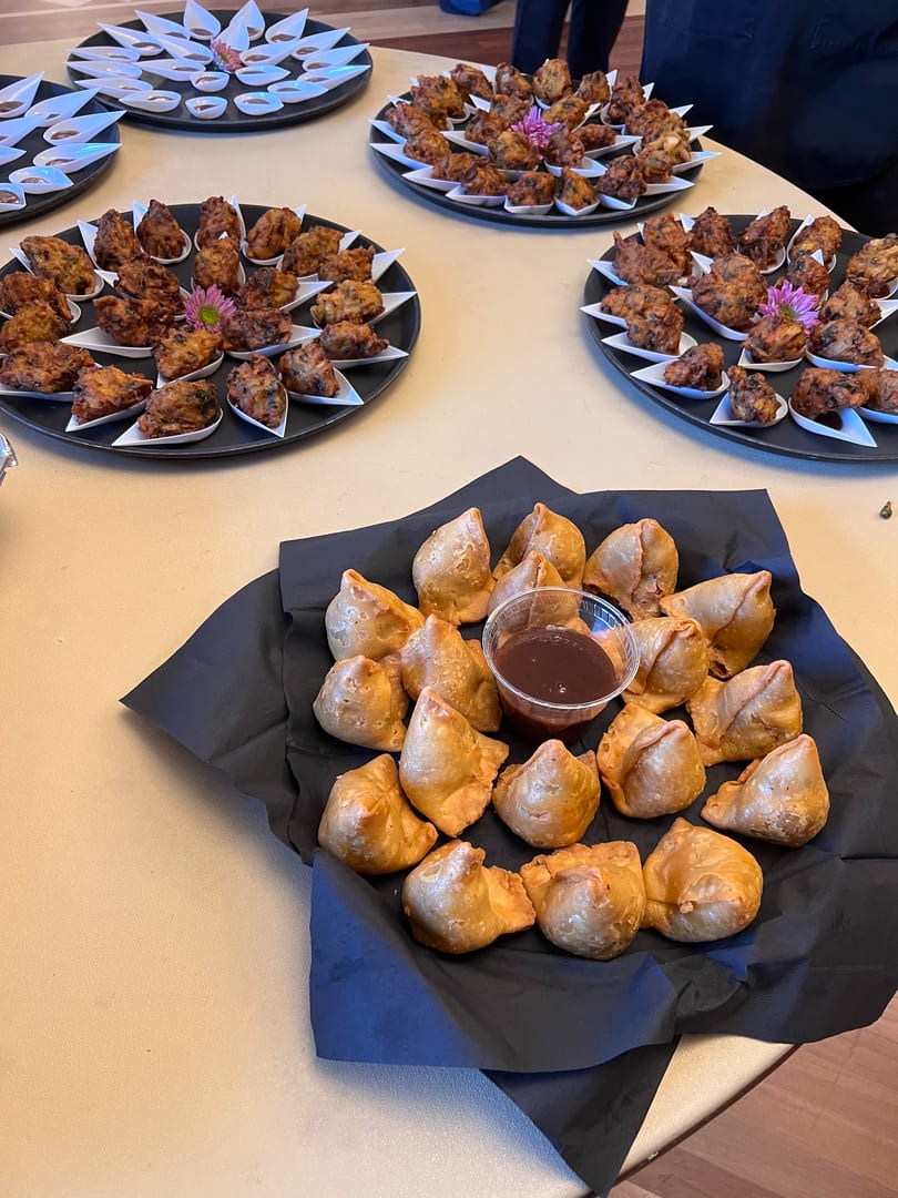 Platters of samosas and pakoras with dipping sauces, ready to be served at an event.